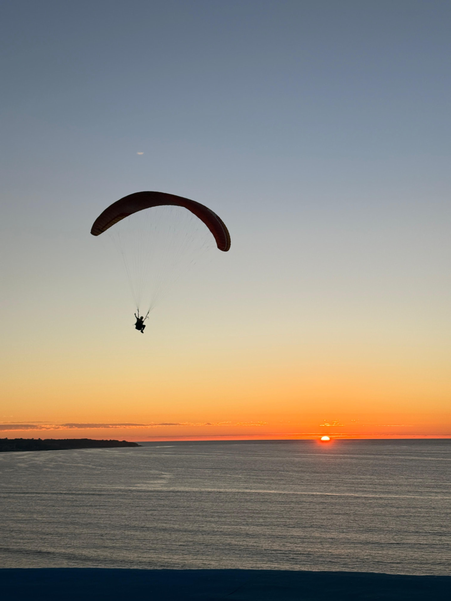 Parapente sobre el océano al atardecer en Maitencillo